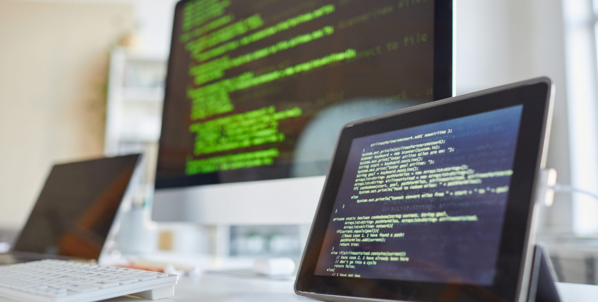 Image of digital tablet and computer monitor with software on the screens on the table at IT office