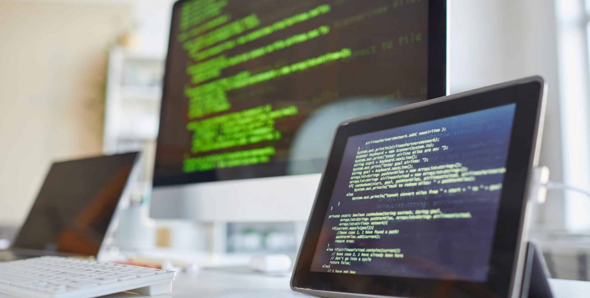 Image of digital tablet and computer monitor with software on the screens on the table at IT office